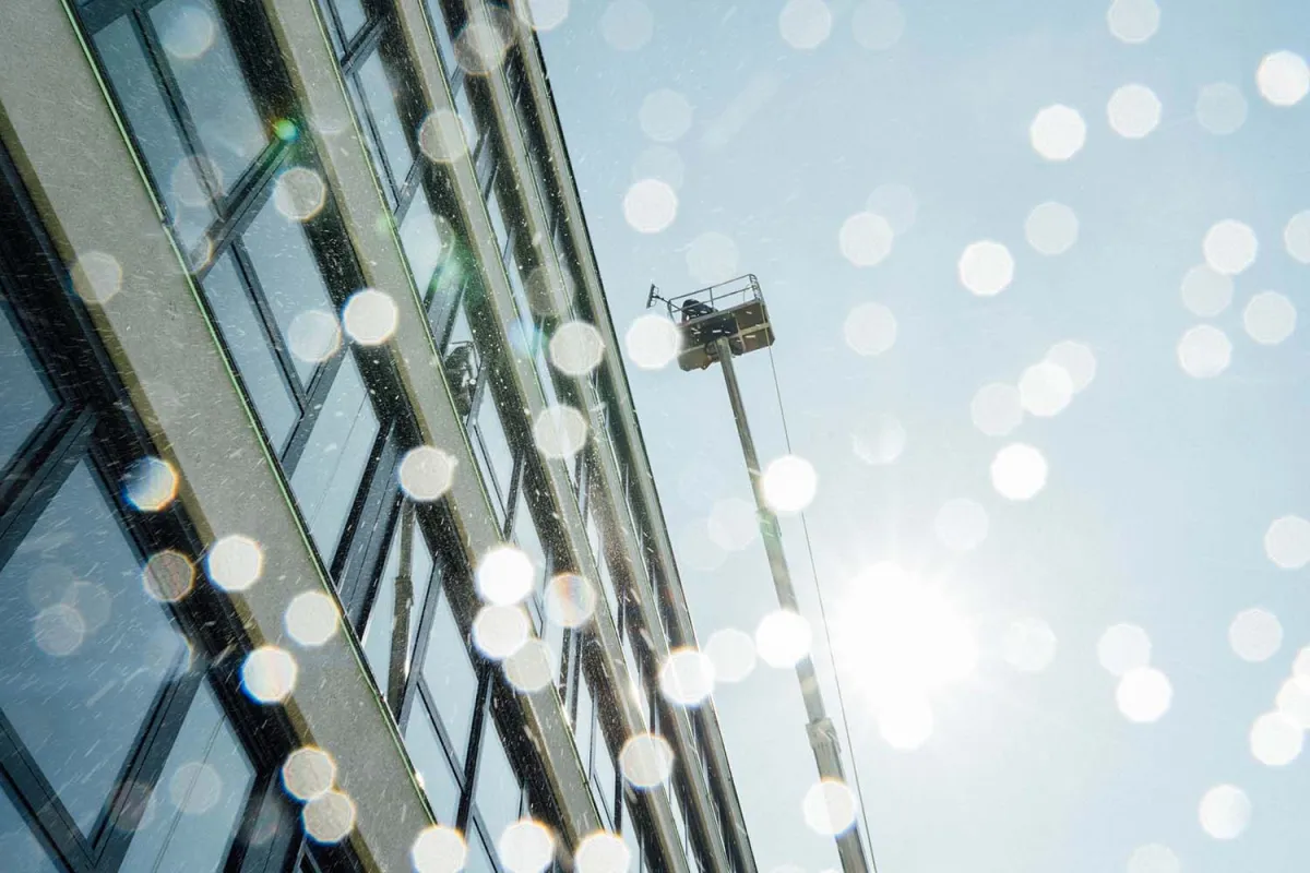 Hubsteiger vor der Glasfassade eines Bürogebäudes im Gegenlicht