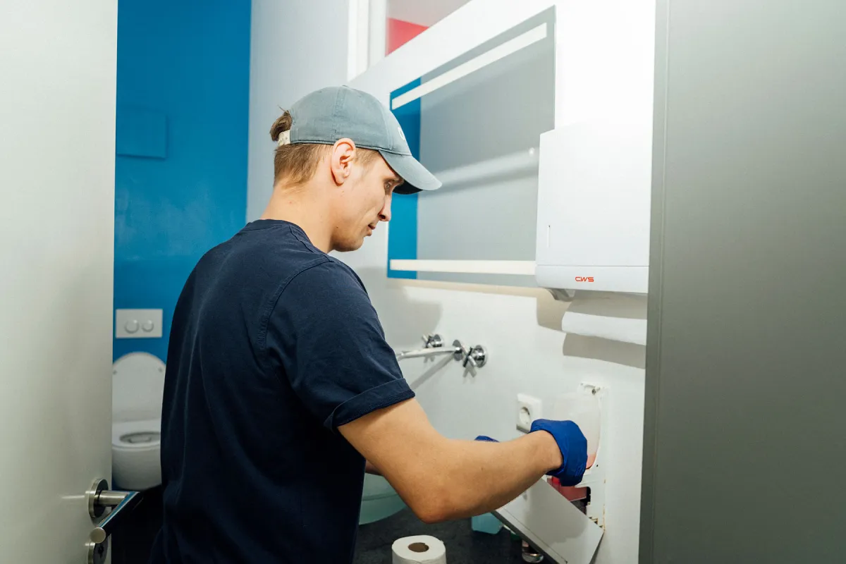 Mitarbeiter reinigt einen Sanitärbereich