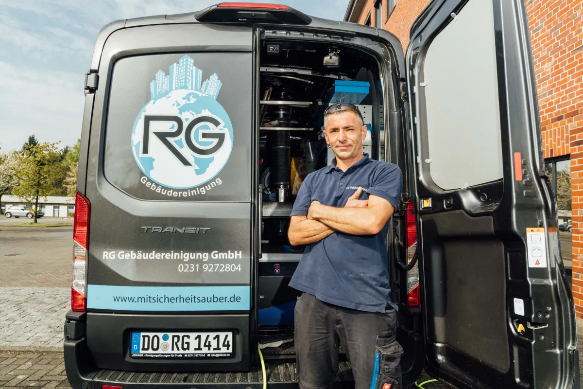 Mitarbeiter vor dem Firmenfahrzeug der RG Gebäudereinigung