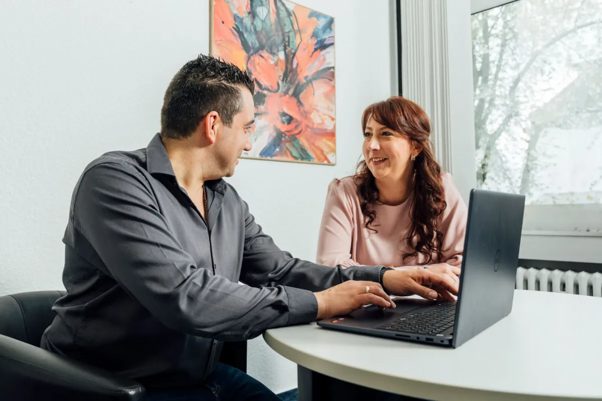 Zwei Mitarbeitende der RG Gebäudereinigung besprechen etwas am Laptop